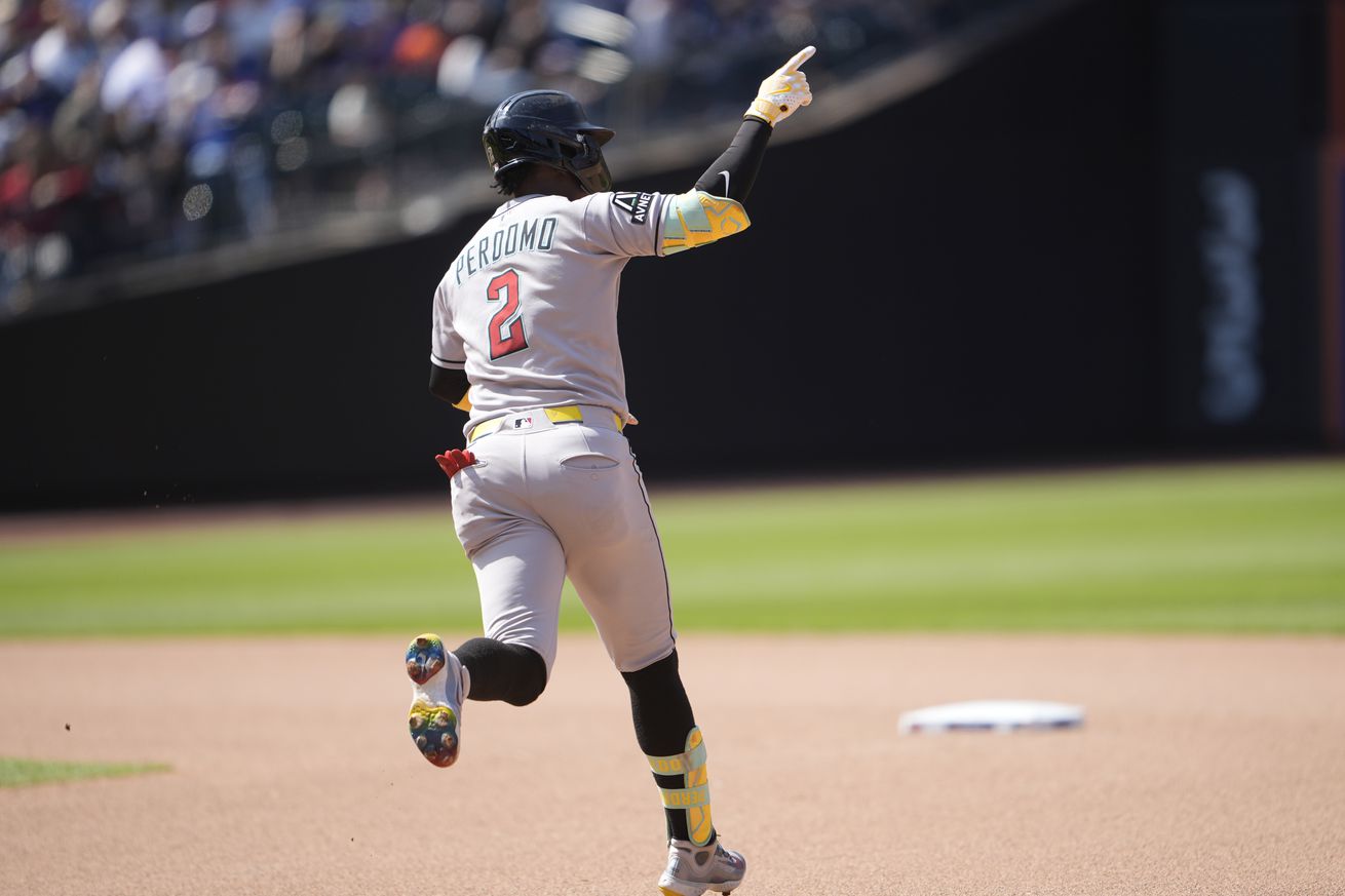 Geraldo Perdomo, facing away from the camera, jogging towards second base while pointing to the outfield following hitting a home run